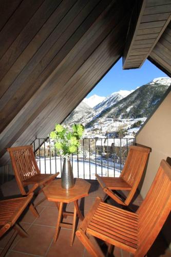 a balcony with three chairs and a table with a vase at Aparthotel Sarrato in Sallent de Gállego
