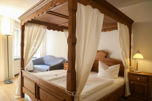 a bedroom with a canopy bed and a chair at Hotel Zwei Länder in Apolda