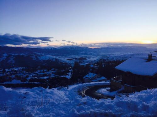 - une vue sur la ville dans la neige au coucher du soleil dans l'établissement Les Appartements Du Père Castor-Self Check-In, à Font-Romeu-Odeillo-Via