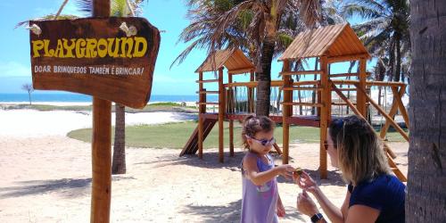 a woman and a little girl standing next to a playground at Atlantic Palace Family inn in Aquiraz