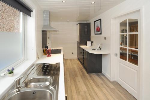 cocina con fregadero de acero inoxidable y ventana en Spacious 3 bedroom house en Stirling