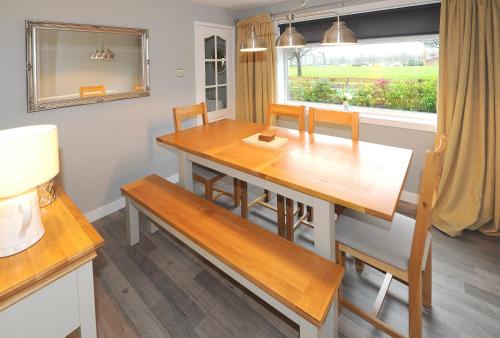 a dining room table with a bench and a window at Three Bedroom Spacious House in Stirling