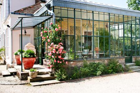 a house with a greenhouse with flowers in front of it at Clos Saint Nicolas in Neauphle-le-Château