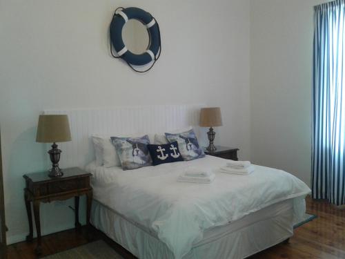 a bedroom with a bed with pillows and a clock on the wall at Jetty Self-Catering in Swakopmund
