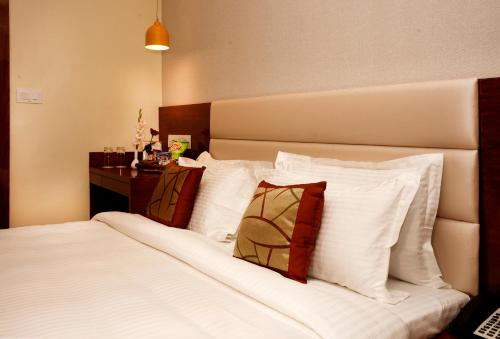 a hotel room with a bed with white pillows at Amalfi Grand in Patna