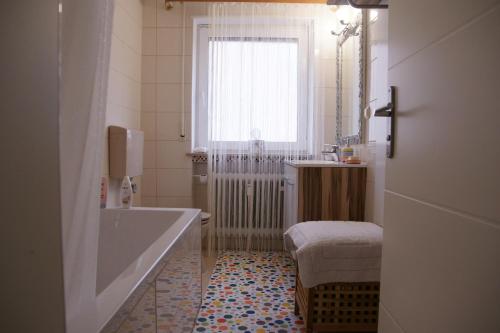 ein Bad mit einer Badewanne, einem Waschbecken und einem Fenster in der Unterkunft Apartment Elena in Bad Wörishofen