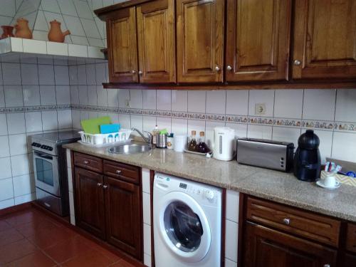 uma cozinha com uma máquina de lavar roupa e um lavatório em Casa da Vovó (Casa do Tapado) em Amarante