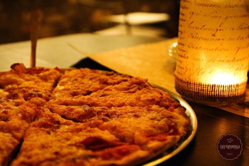a pizza on a table next to a bottle of beer at Hotel Papanikola in Piána