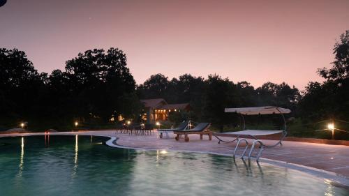 a swimming pool with a table and a bench next to it at Tathastu Kanha in Kānha