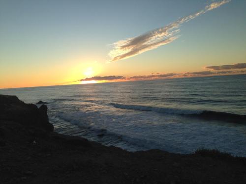 a sunset on the beach with the ocean at Un Thé Au Bout Du Monde in Mirleft