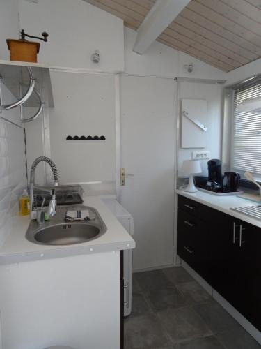 une cuisine blanche avec un évier et un comptoir dans l'établissement Gîtes, Chambres d'Hôtes La Maison d'Amis, à Puilboreau