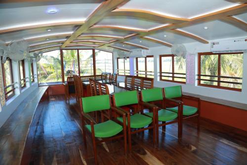 a dining room with a table and green chairs at Beach Paradise Day Cruise Houseboat in Alleppey