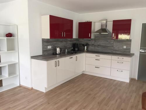 an empty kitchen with white cabinets and red cabinets at ruhige Souterrainwohnung in Leverkusen