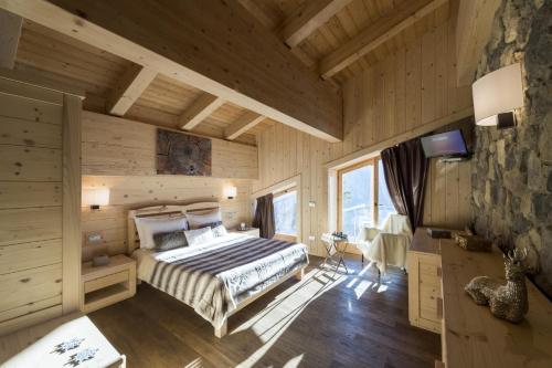1 dormitorio con 1 cama en una habitación de madera en Chalet Morel 1586 Hotel & Spa, en Limone Piemonte