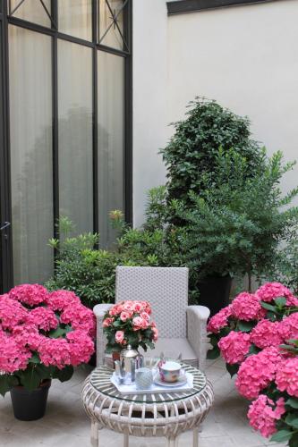 a patio with pink flowers and a table and chairs at My Home In Paris in Paris