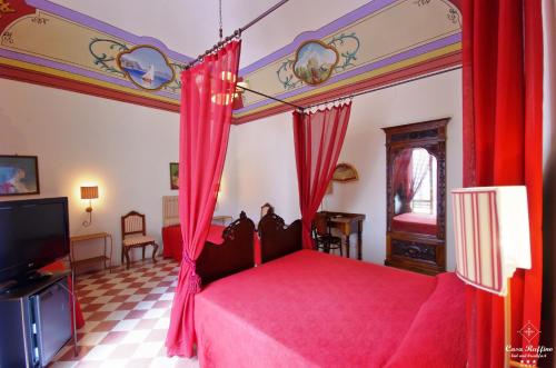 1 dormitorio con 1 cama con cortinas rojas y TV en B&B Casa Ruffino, en Balestrate