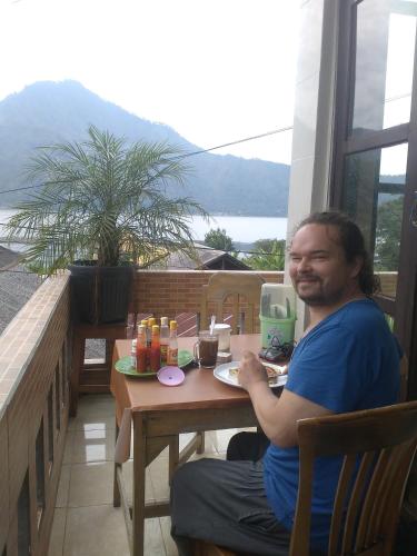 a man sitting at a table with a plate of food at Volcano Living in Kintamani