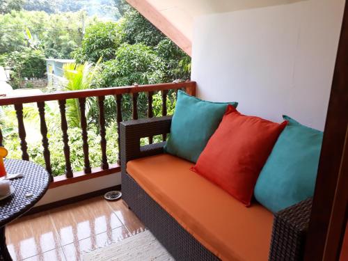 a balcony with a bench with colorful pillows on it at Chloe's Cottage Self-Catering in La Digue