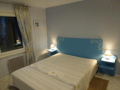 イラウーゼルヌにあるMaison de MANONのベッドルーム1室(青いヘッドボード付きのベッド1台、窓付)