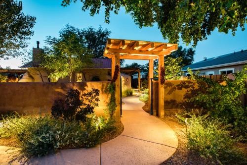 a wooden pergola in a garden with a sidewalk at Casa La Huerta in Albuquerque