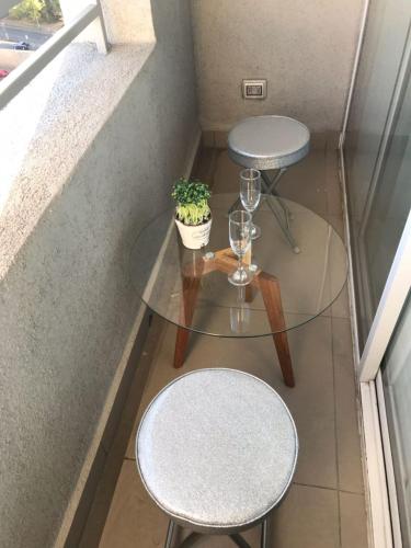 a glass table and two stools and a plant at Full Moneda 909 in Santiago