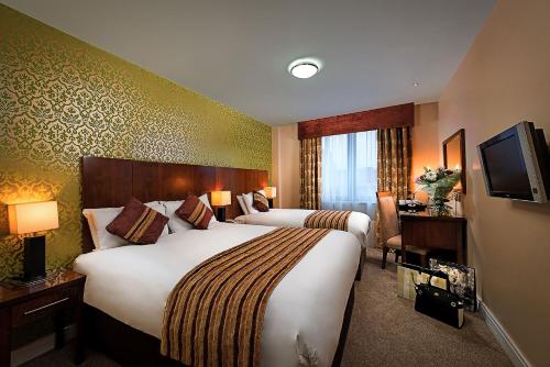 a hotel room with two beds and a television at George Limerick Hotel in Limerick