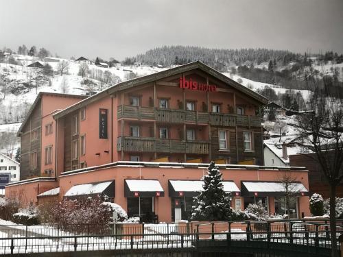 a large pink building with a snow covered mountain at ibis La Bresse Gérardmer in La Bresse