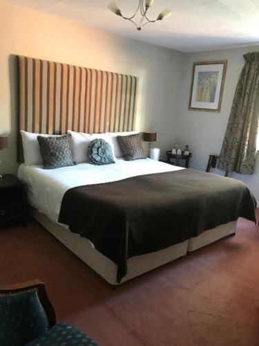 a bedroom with a large bed with a large headboard at The Pytchley Inn in West Haddon