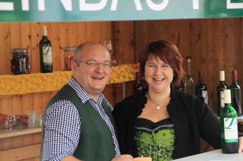 a man and a woman standing at a counter with wine bottles at Pension Peterhof in Mörbisch am See