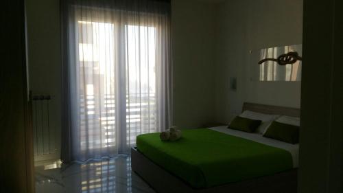 ポルト・チェザーレオにあるB&B La Lagunaのベッドルーム(緑のベッド1台、大きな窓付)