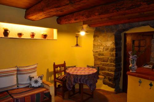 Habitación con mesa, sillas y pared de piedra. en Casa Alba Ara en Oto