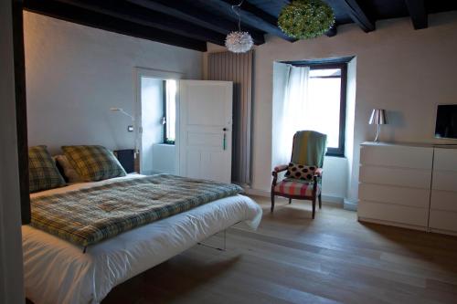 a bedroom with a bed and a chair and a window at Maison Eth Bordac & Bordac Petit in Cazeaux-de-Larboust