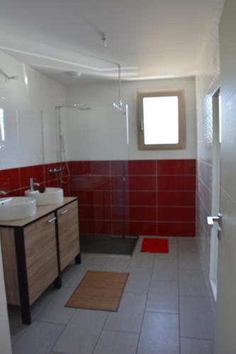 baño con 2 lavabos y pared roja en Maison bord de mer avec jacuzzi, en Névez