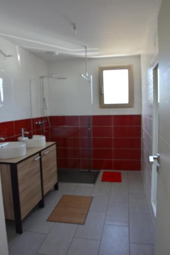 a bathroom with two sinks and a red wall at Maison bord de mer avec jacuzzi in Névez