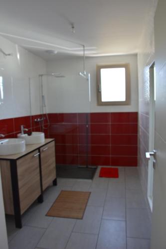 ネヴェにあるMaison bord de mer avec jacuzziの赤い壁のバスルーム(シンク2台付)