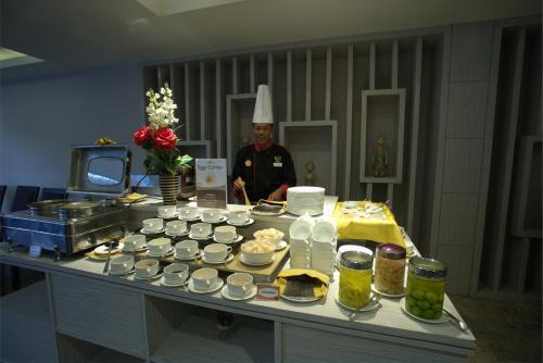 a chef standing in a kitchen with a table of food at Tjokro Hotel Pekanbaru in Pekanbaru