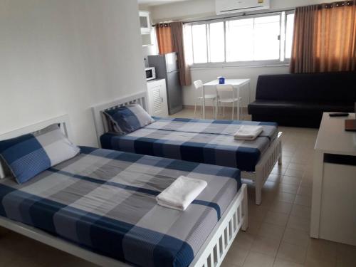 a bedroom with two beds and a living room at New Room in Nonthaburi