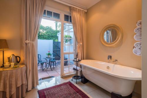 a bathroom with a tub and a patio at Westville Bed and Breakfast in Durban