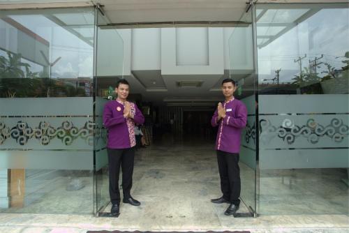 two people standing in front of a glass wall at Tjokro Hotel Pekanbaru in Pekanbaru