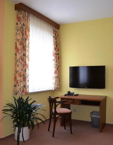 a room with a desk and a television and a window at Hotel Drei Kronen in Frauenwald