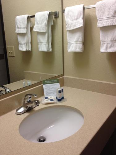 a bathroom with a sink and a mirror and towels at AmericInn by Wyndham McAlester in McAlester