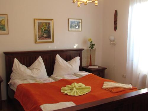 a bedroom with a bed with an orange blanket at Torkolat Panzió in Tokaj