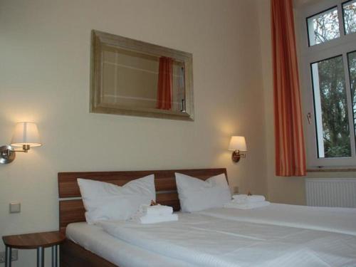 1 Schlafzimmer mit 2 weißen Betten und einem Fenster in der Unterkunft Ferienwohnung Villa im Park in Wangerooge