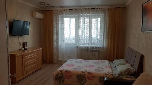 a bedroom with a bed and a television and a window at Apartments Avrora, Gagarina 75 in Oryol