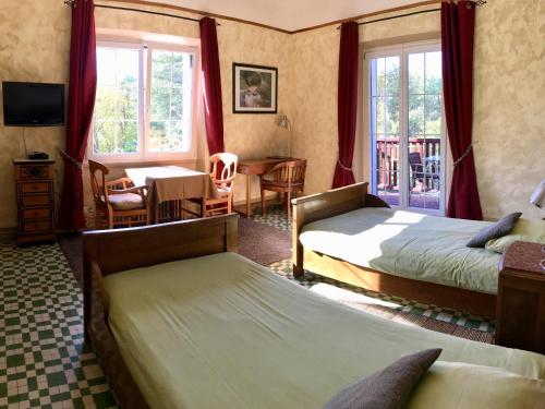 a bedroom with two beds and a table and a desk at La Villa du Parc in Prades