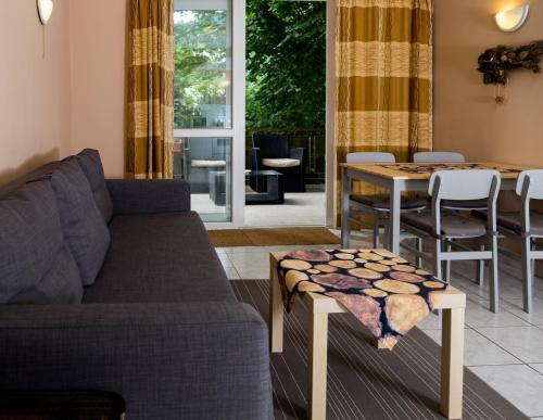 a living room with a couch and a table at Vadásztanya Apartmanházak in Siófok