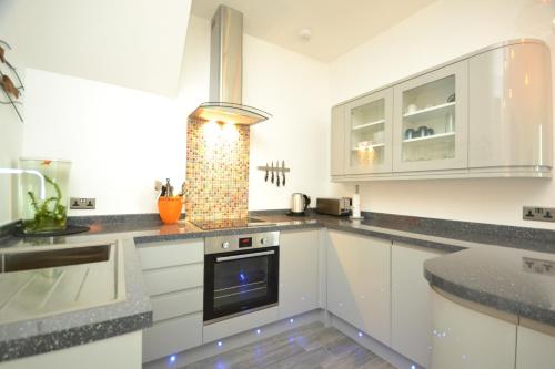 a kitchen with white cabinets and a stove at SeaScape in Bexhill