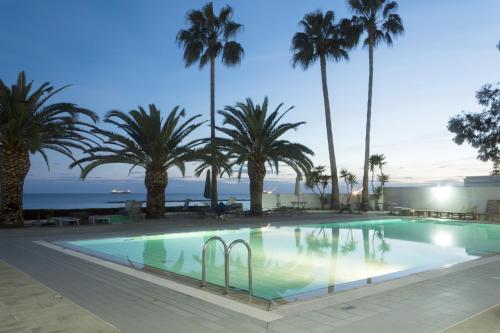 een zwembad met palmbomen en de oceaan op de achtergrond bij Solferino 67 West with pool in Limassol