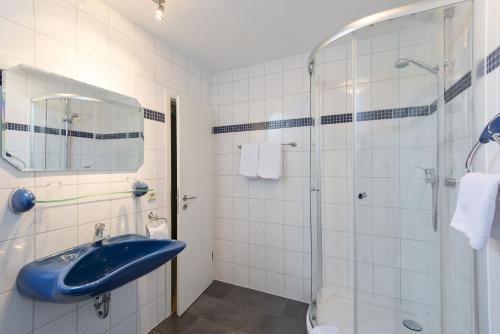 La salle de bains est pourvue d'un lavabo bleu et d'une douche. dans l'établissement Gaestehaus Gaes, à Trittenheim