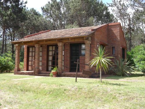 a small brick house with a palm tree in the yard at Adi y Dina Cabañas in La Paloma